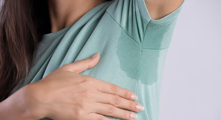 A woman wearing a green shirt with a visible sweat stain under her arm
