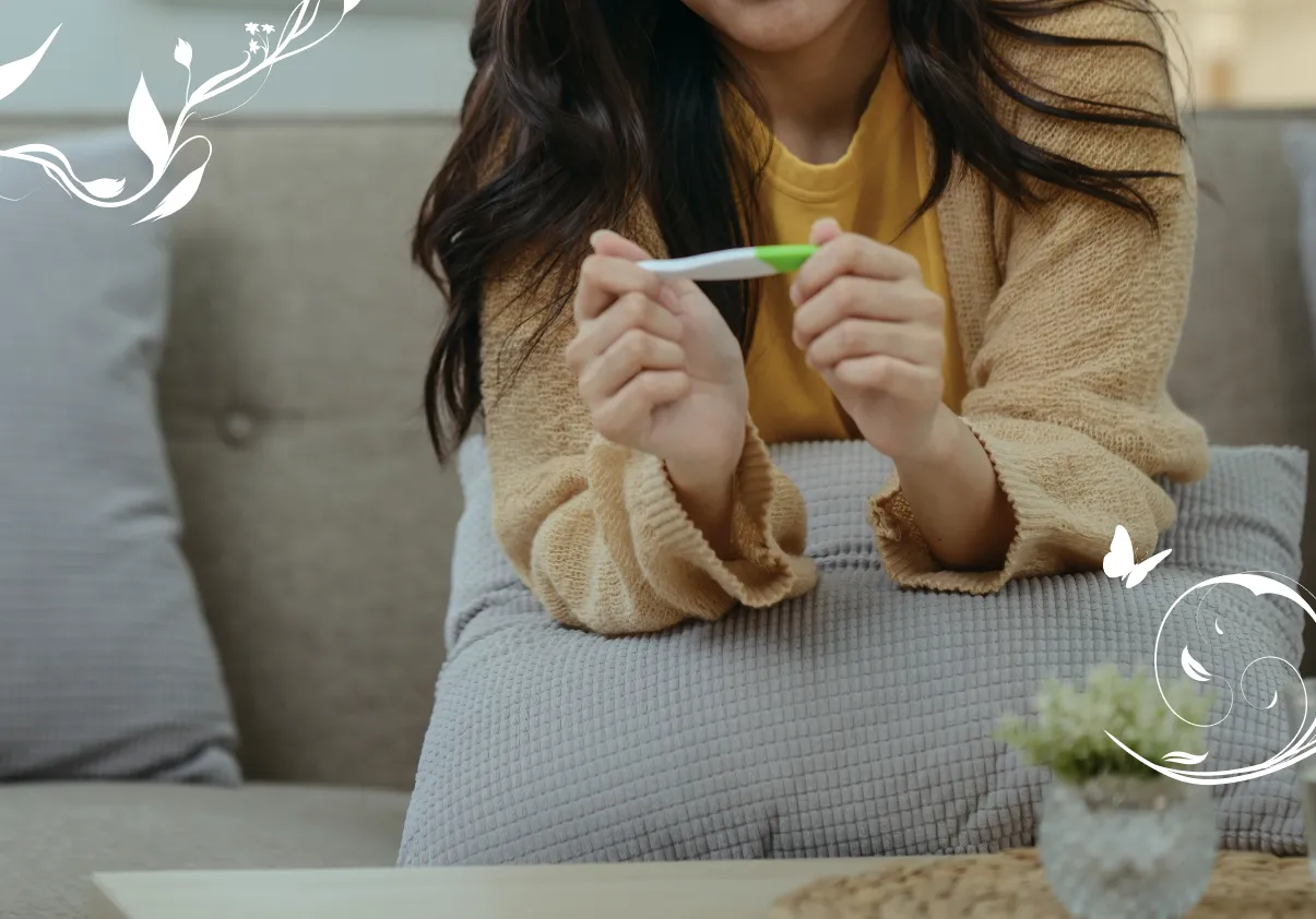 Woman sitting on a sofa and holding a pregnancy test.